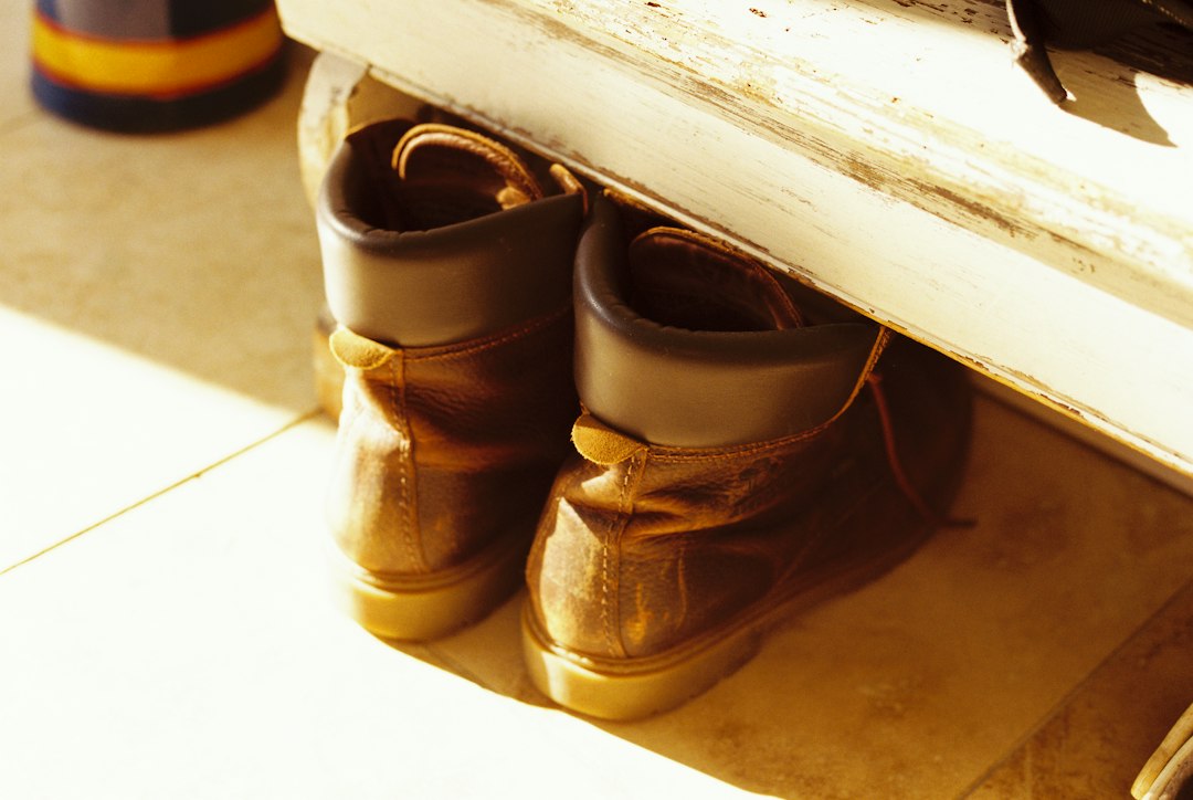Worn leather boots under bench in sunlit hallway