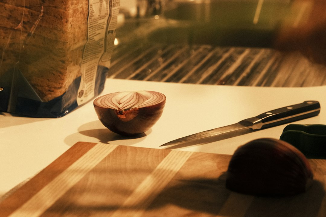 Red onion halves on a cutting board with a knife