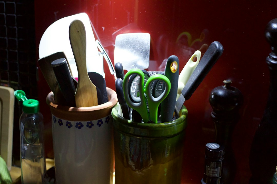 Kitchen utensils including spoons, knives, and scissors in containers