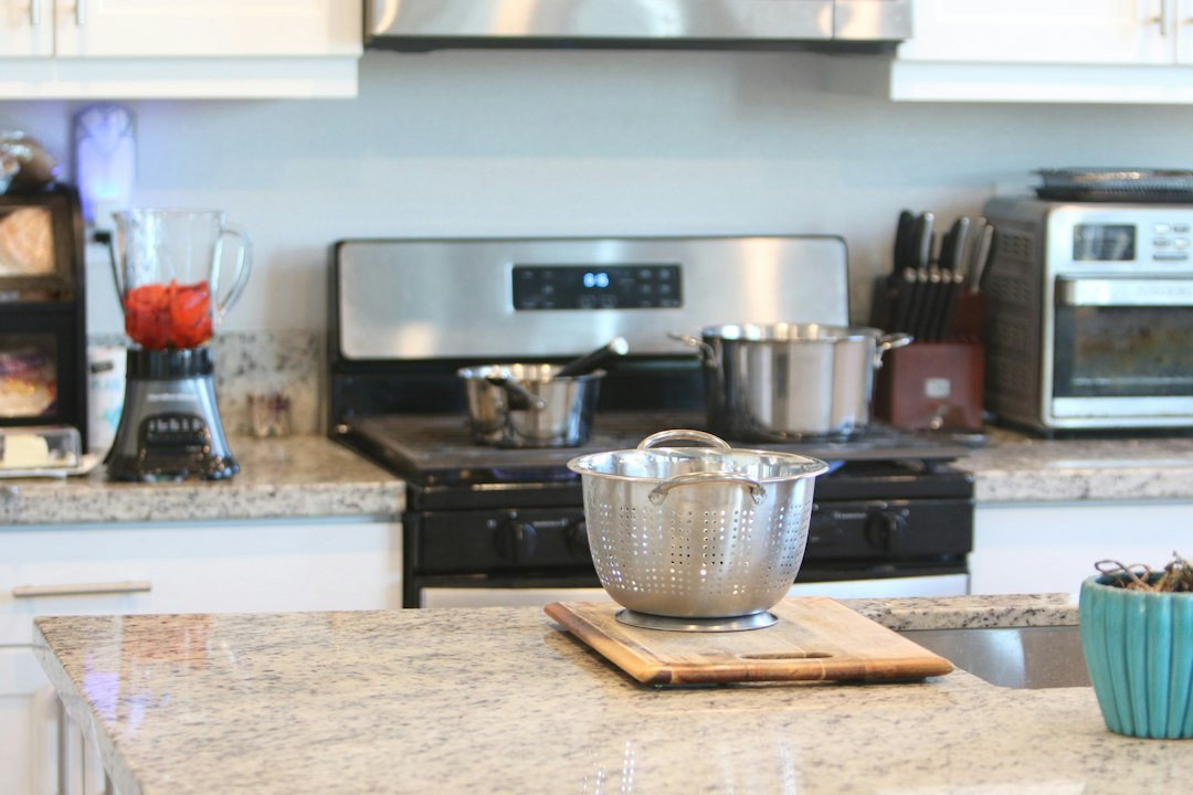 A modern kitchen with a colander, stove, and blender
